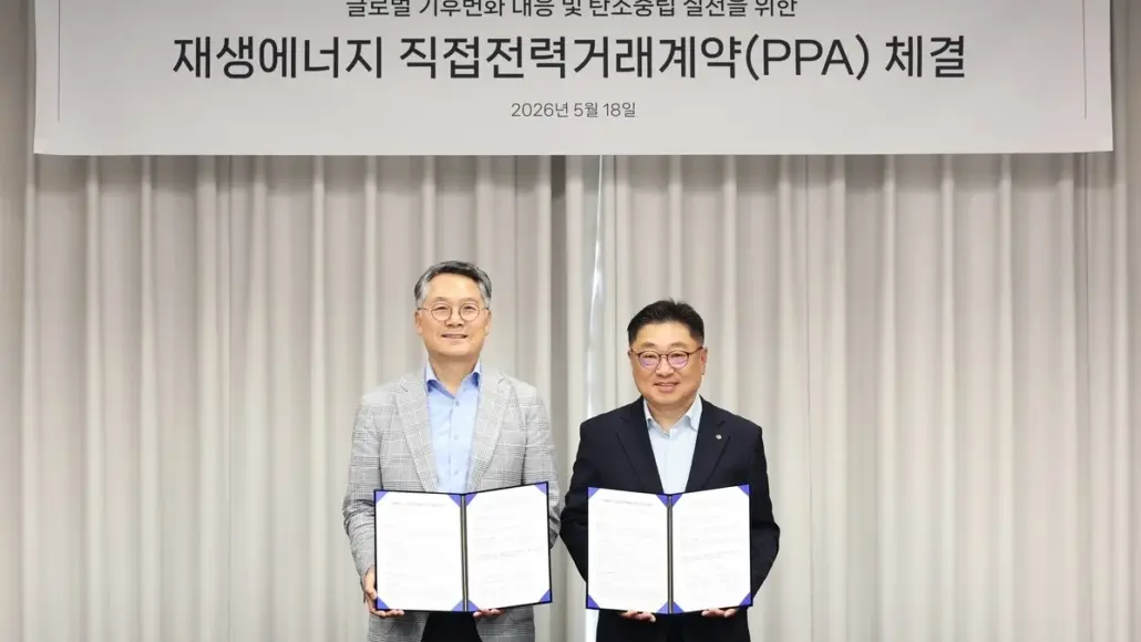 Two men in suits hold open signed documents at a renewable energy PPA signing ceremony, with a banner in Korean above them.