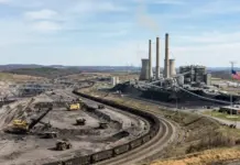 Trump Announces $700 Million Investment to Boost U.S. Coal Coal mine and power plant with excavators, coal piles, and a long freight train near the facility; US flag visible nearby.