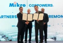 Mikro MSC, HKCT to Advance BESS Projects Across Malaysia Four men in suits on a stage hold open signed documents and shake hands during a partnership ceremony, with a blue backdrop reading 'Mikro' and 'PARTNERSHIP CEREMONY'.