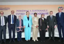 EU-Kuwait Energy Roundtable Eyes Closer Energy Cooperation Group of eight professionals in formal attire posing in front of a banner reading “Powering a Sustainable Energy Future Together” at an EU–Kuwait relations event.