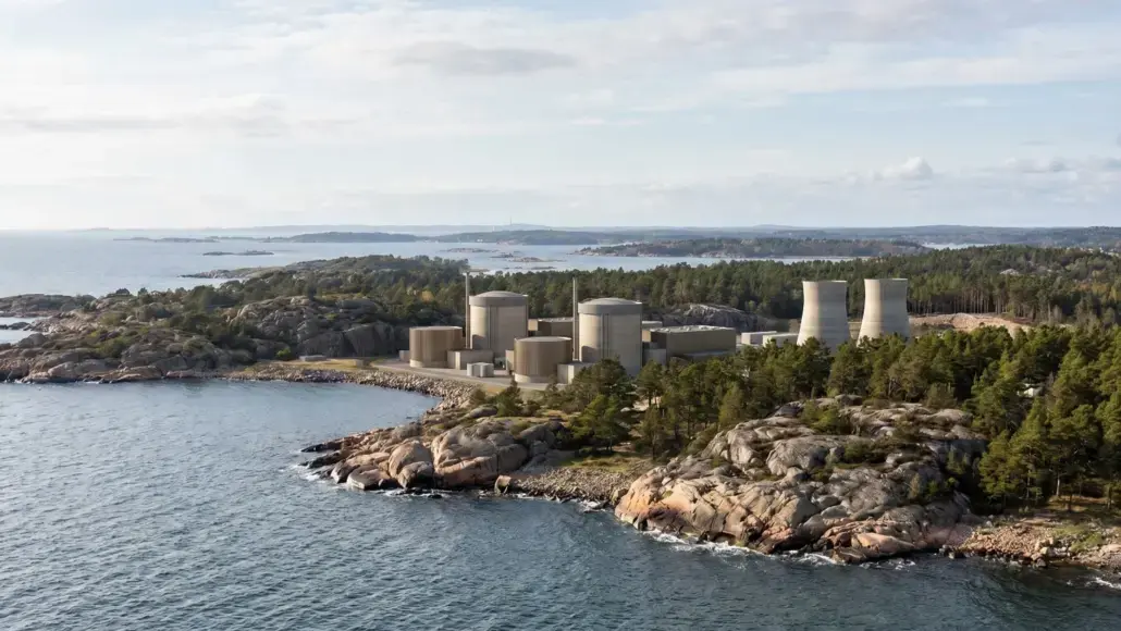 Industrial complex with cylindrical tanks and cooling towers on a rocky coastline, surrounded by trees and sea.