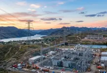 Türkiye Plans TANAP-like Electricity Corridor to Azerbaijan Large power substation with transformers and metal framework, power lines crossing rolling hills beside a river at sunset.