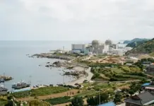South Korea Decides on Sites for Two New Nuclear Reactors Coastal nuclear power plant with two domed cooling towers near the sea and harbor in front.