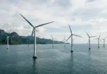 Philippines Strengthens Framework for GEA-5 Offshore Wind Offshore wind farm with multiple wind turbines standing in calm sea and a distant mountainous coastline behind them.