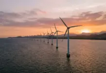 Philippines Advances Offshore Wind Farm for Energy Security Offshore wind turbines lined up in the sea at sunset, with calm water and distant hills on the horizon.