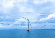 China Becomes First to Power Up 16MW Floating Wind Platform Offshore wind turbine standing in calm blue ocean under a partly cloudy sky, with three blades visible.