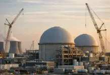 U.S. Advanced Nuclear Project Gets $1B More Federal Funding Nuclear power plant with two large domed reactors under construction, surrounded by scaffolding and cranes at sunset.
