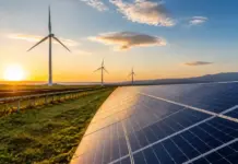 ABB Taps LevelTen Energy for Clean Energy Procurement Sunset over a solar farm with rows of solar panels in the foreground and wind turbines in the distance.