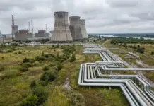 Canada, Ukraine Advance Energy Cooperation Efforts Industrial power plant with large cooling towers and extensive above-ground piping in a flat, rural landscape.